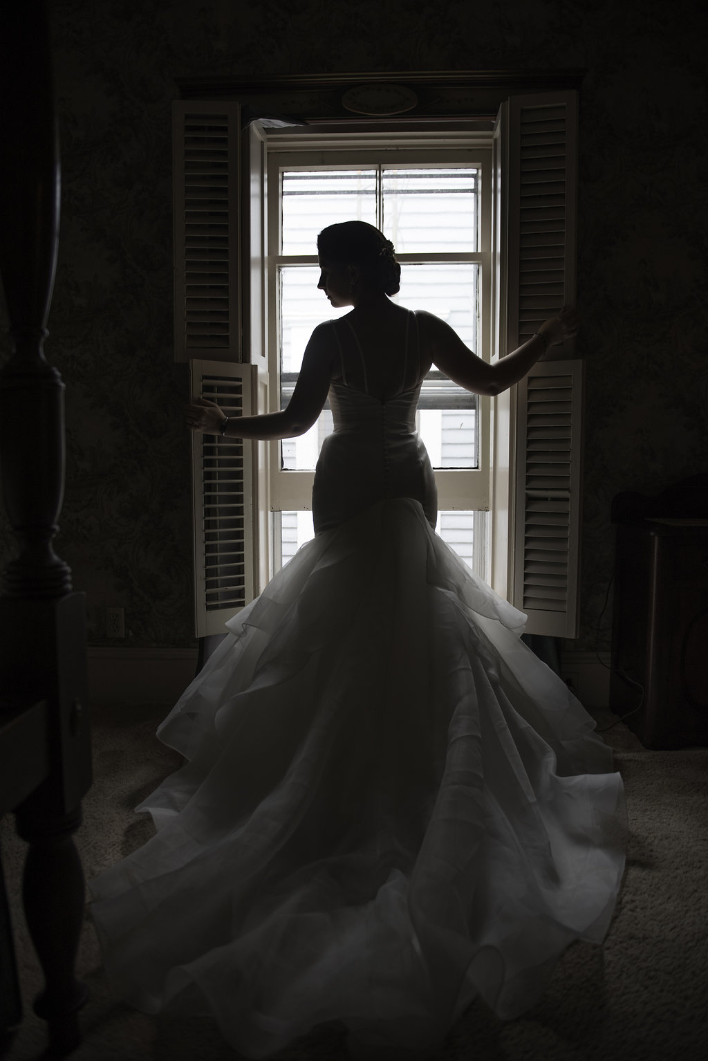 Silhouette of bride standing in front of window