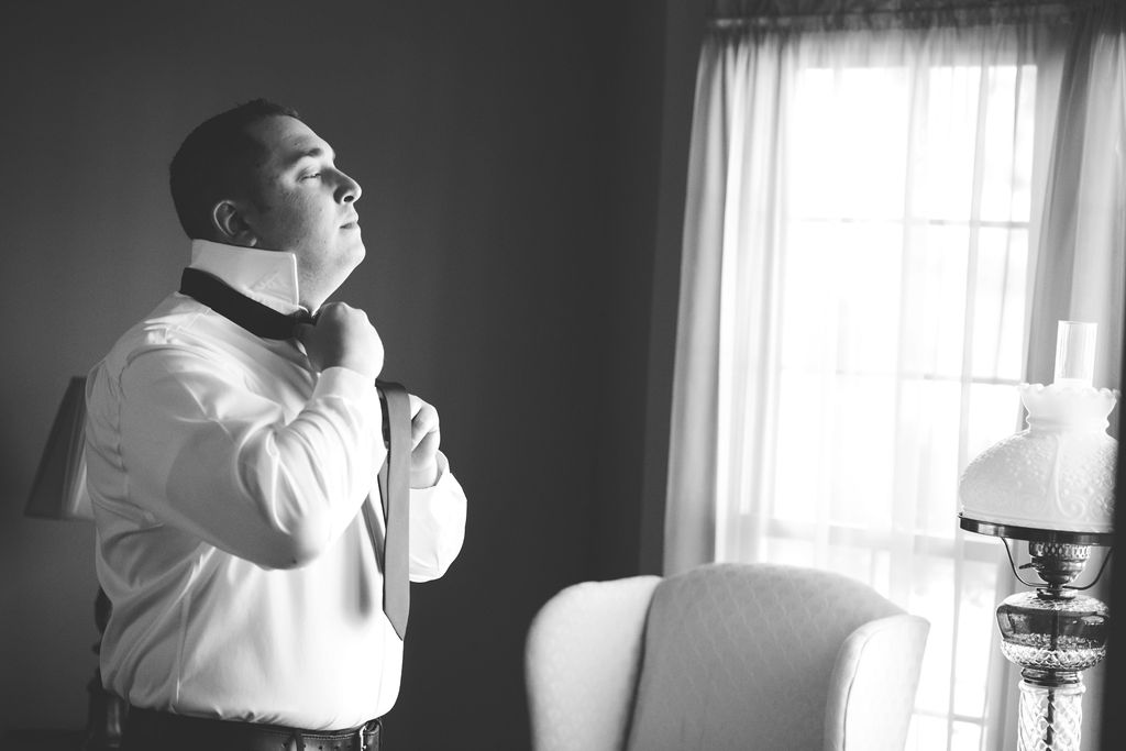 Groom adjusts tie as he gets ready for the wedding day