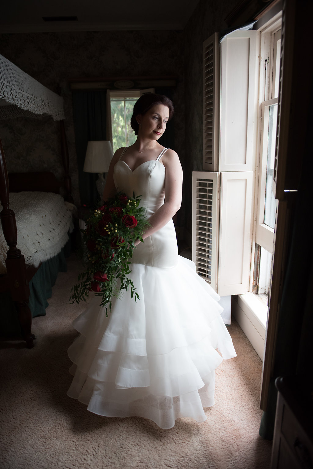 Elegant bride glances down her shoulder towards the window in the getting ready space