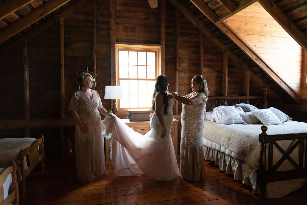Bride getting he final touches on her dress in a rustic getting ready space | choosing a getting ready space on your wedding day 