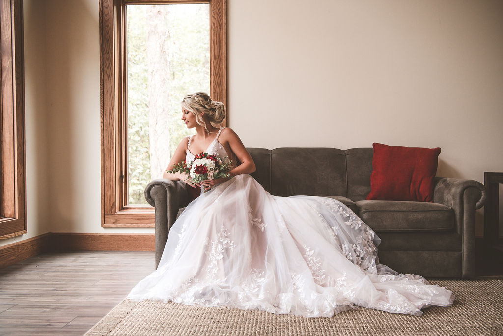 Bride sitting elegantly on couch looking over her shoulder holding her bouquet | choosing a getting ready space on your wedding day 