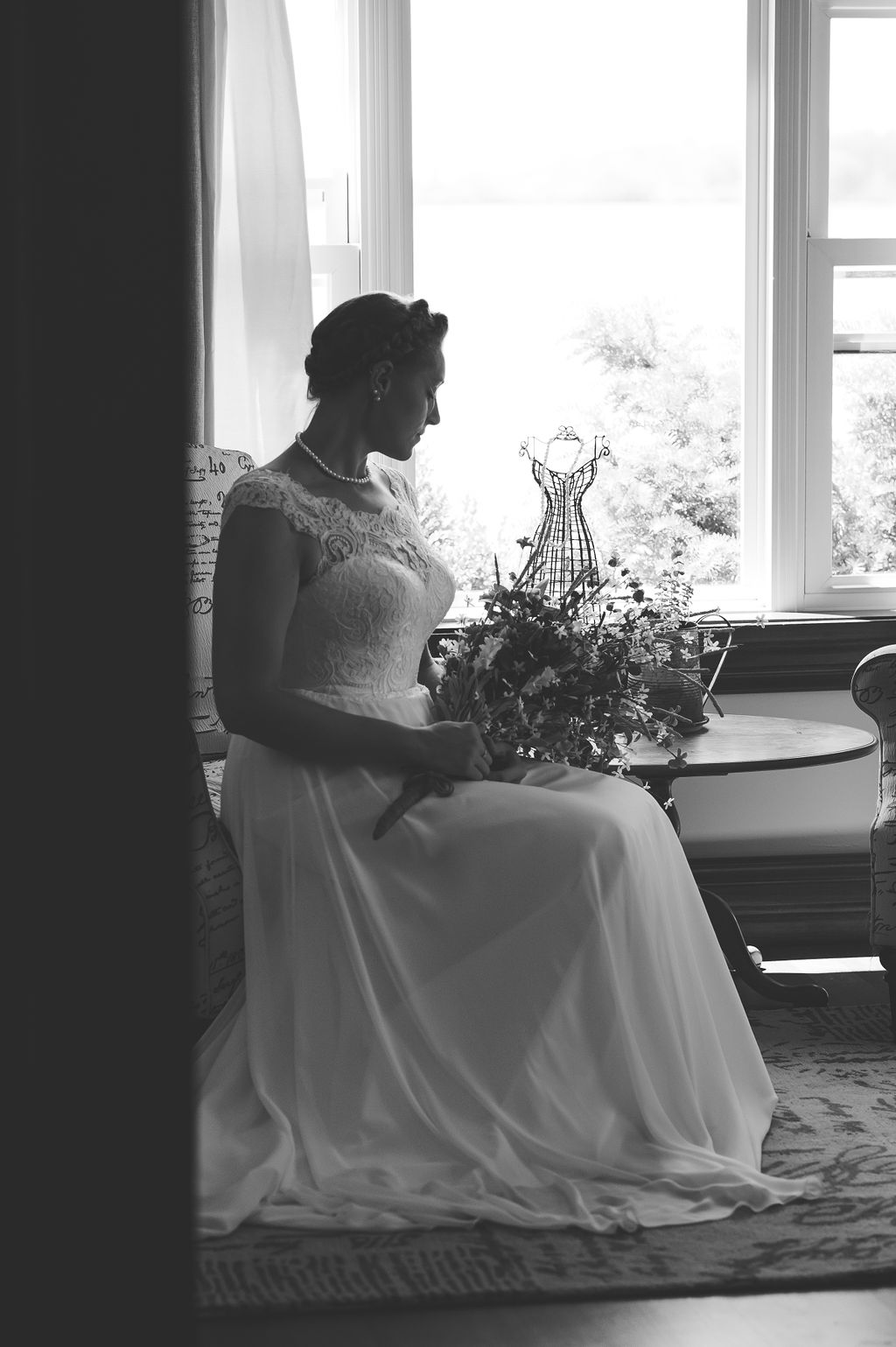 Black and white portrait of bride in front of a window holding her bouquet | tips for choosing a getting ready space
