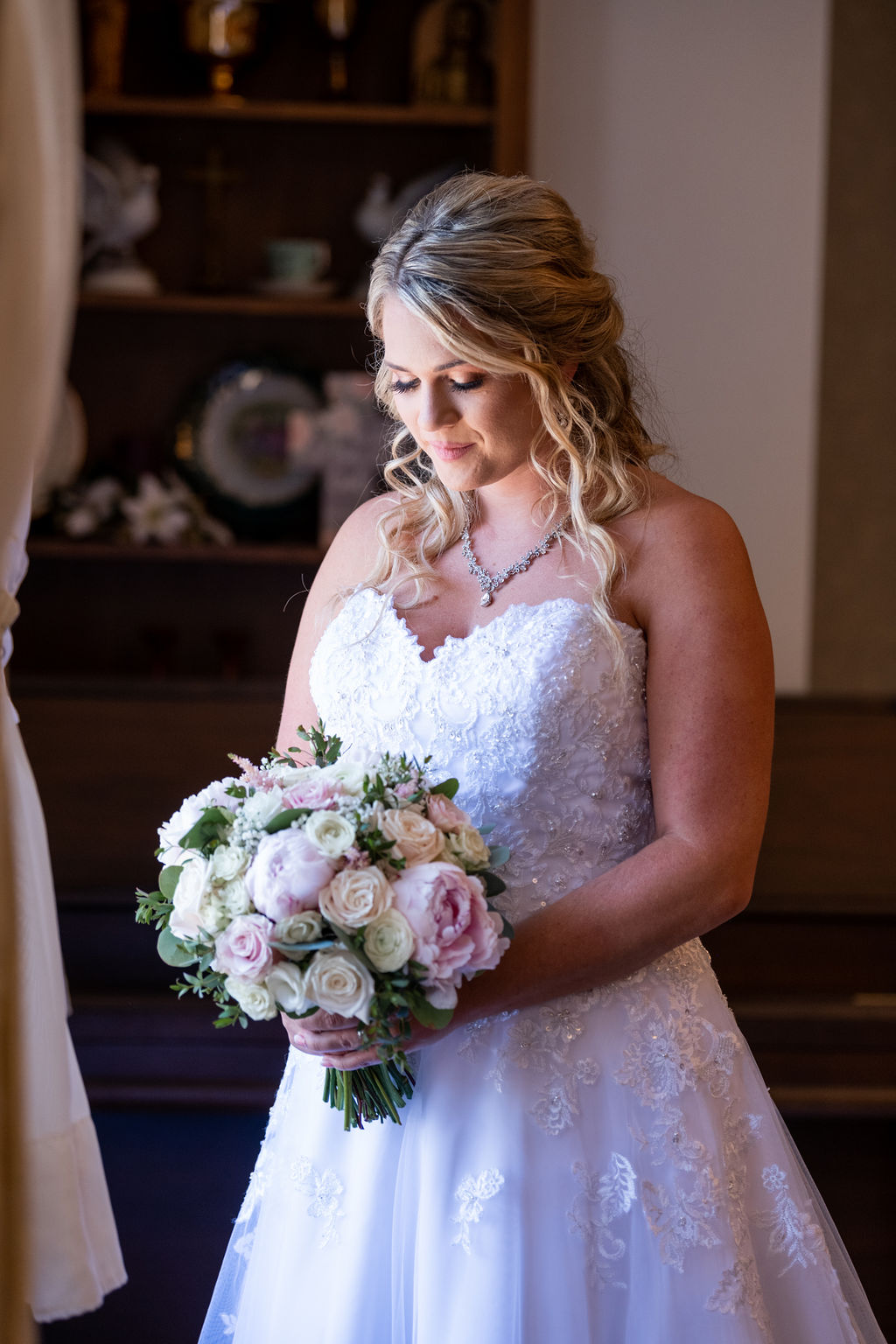 Bride smiles down at her bouquet | tips for choosing a getting ready space