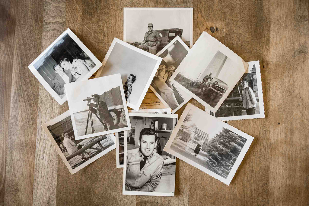 Collection of old, black and white photographs arranged on the floor. 