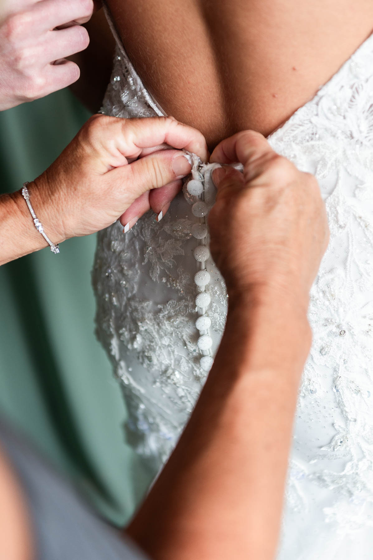 Mom buttoning daughter's bridal gown