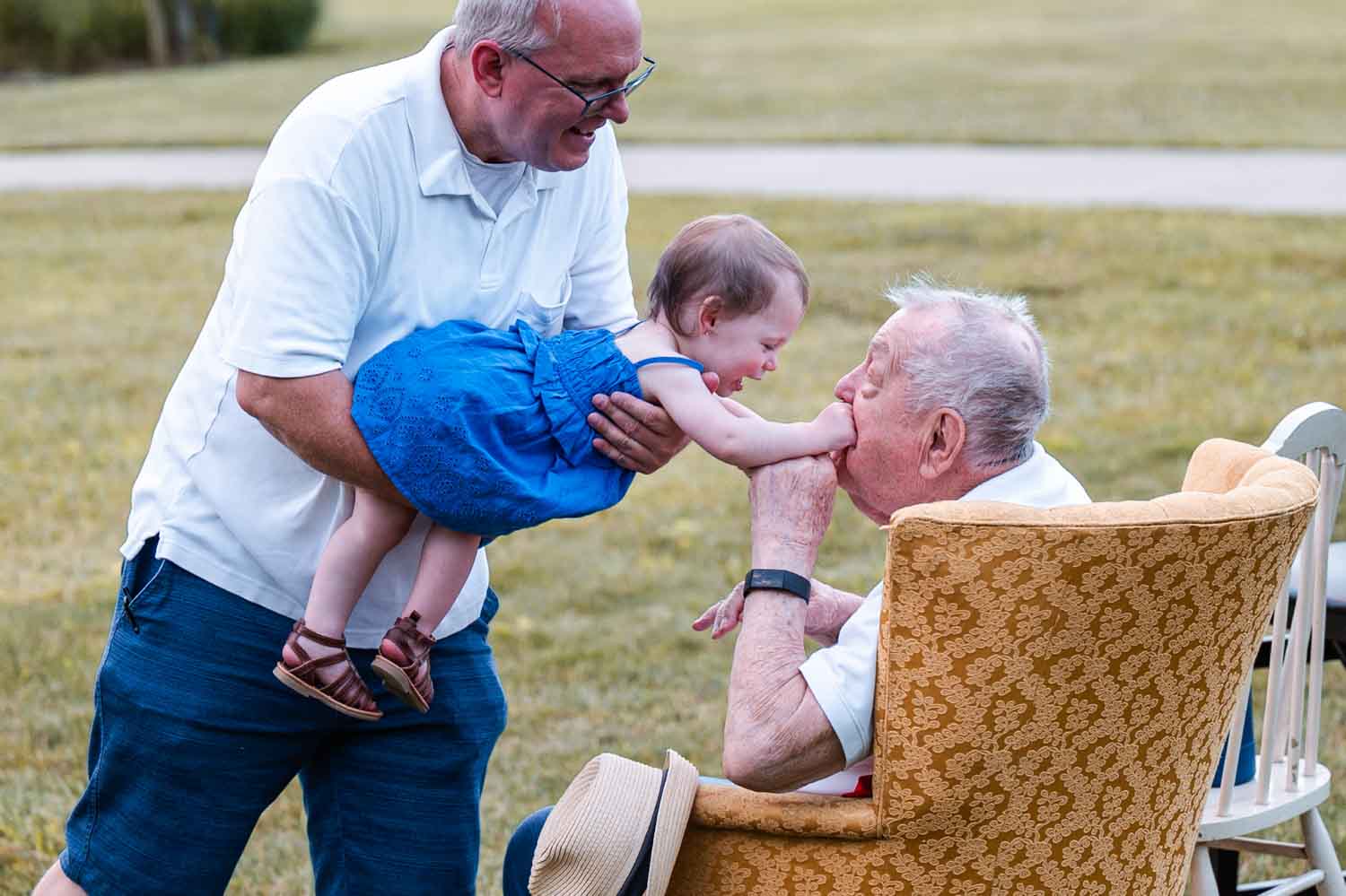 Grandpa kissing his great granddaughter's hand