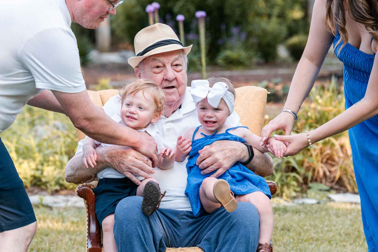 Mom and dad sitting their twin toddlers on Great Grandpa's lap
