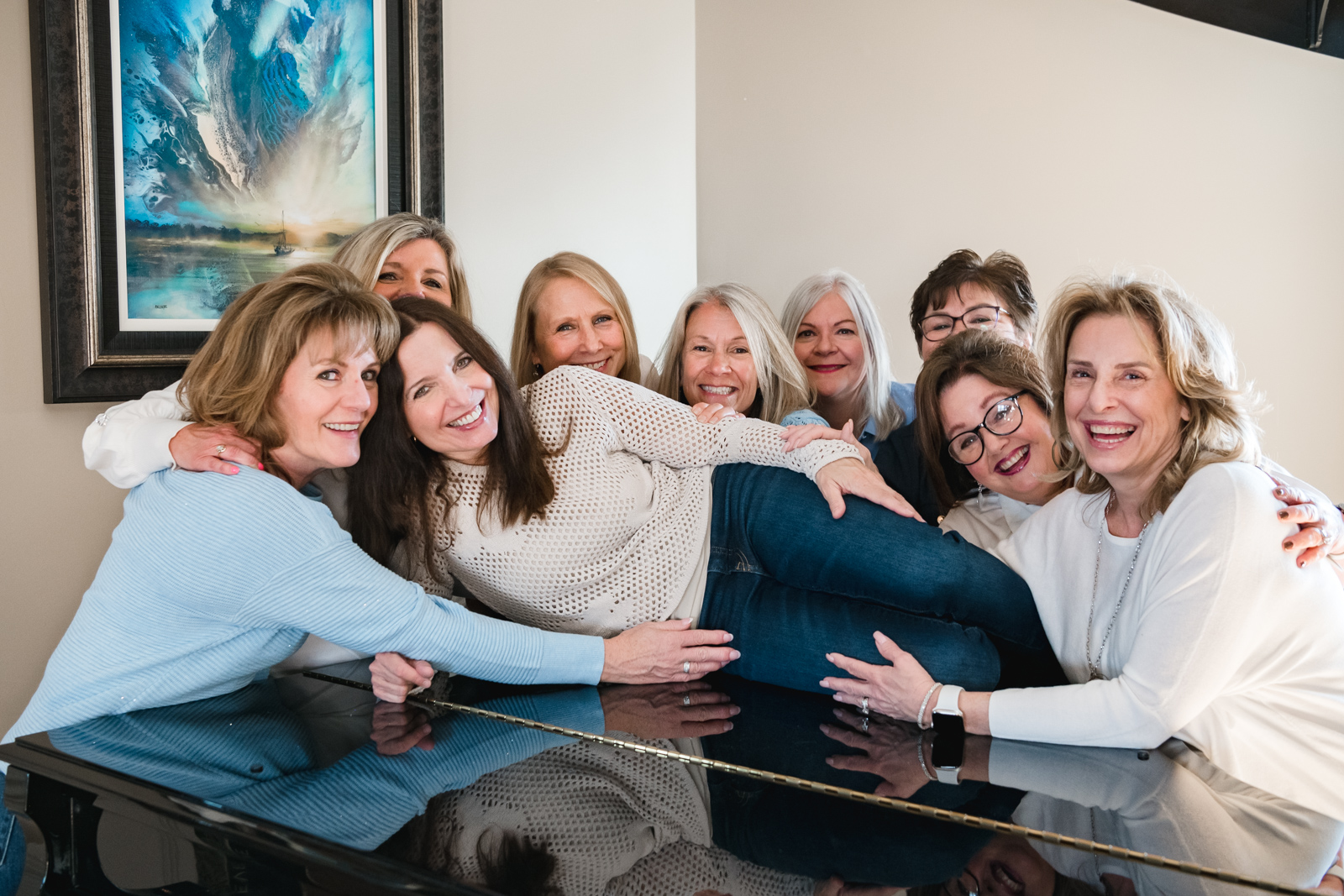 Group of Ladies surrounding their friend on top of a piano