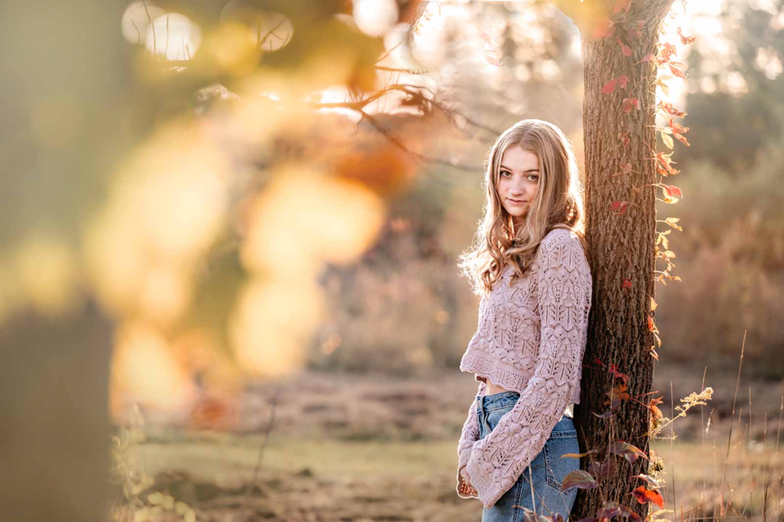 Senior Girl leaning against a tree in a fall setting